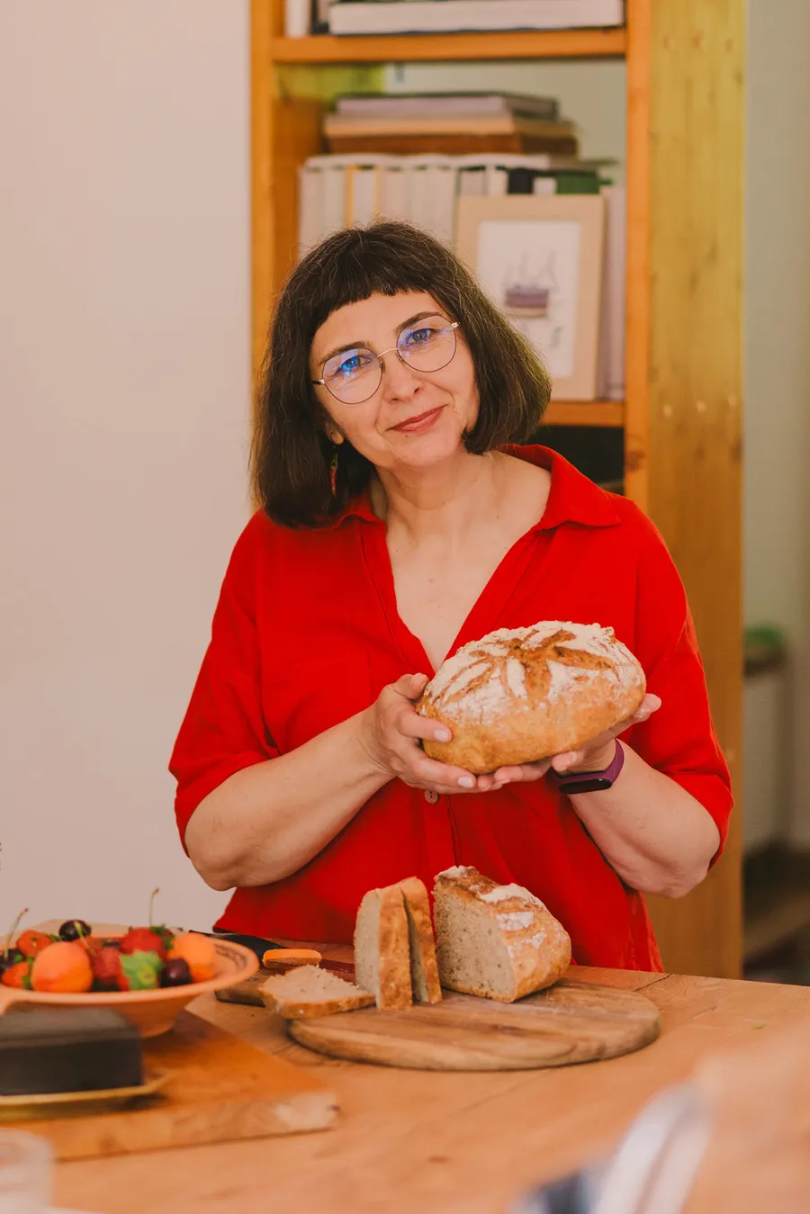 Dana Burlacu Vistiernicu cu o pâine artizanală în mâini, la masa din bucătărie