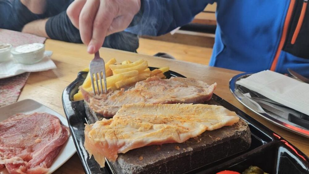VIDEO | Experiență culinară inedită la baza pârtiei: Locul unde poți mânca friptură pe piatră încinsă, pregătită chiar de tine! Nu te aștepta la fine dining, ci la o masă autentică, gustoasă și mai ales ... accesibilă!