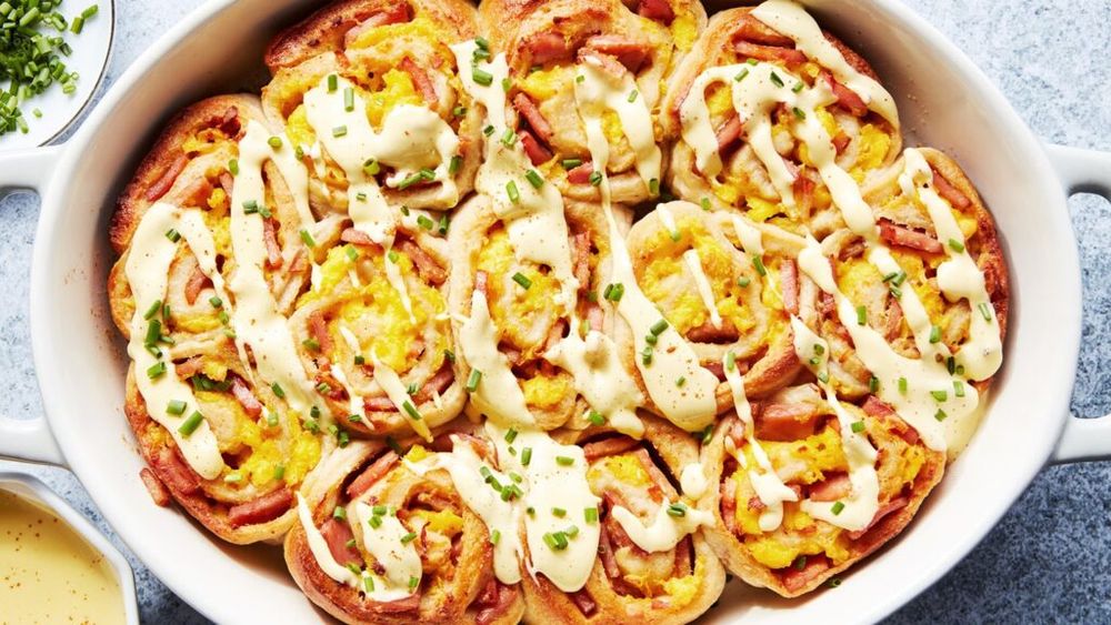 Rulouri inspirate de ouăle Benedict, cu bacon, ouă și sos hollandaise cremos / Rețeta transformă preparatul tradițional într-un mic dejun la tavă, ideal pentru a fi împărțit cu familia sau prietenii