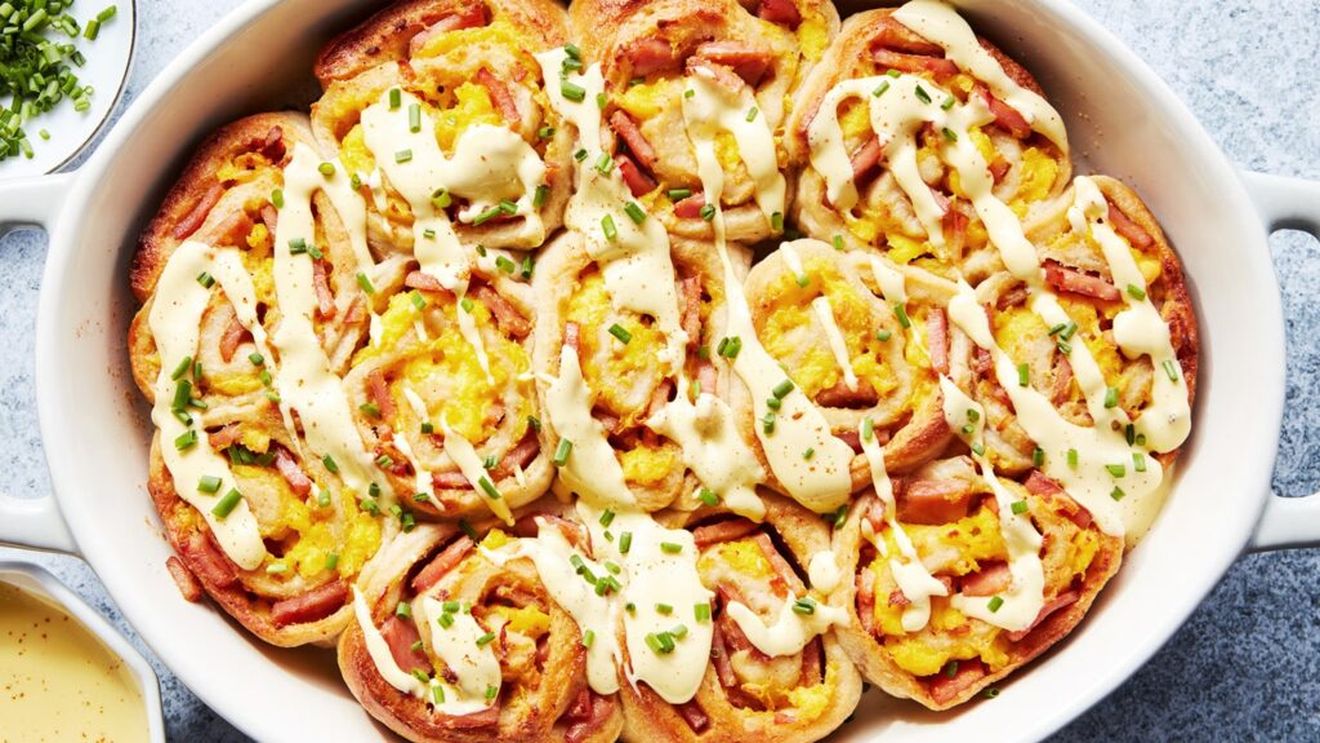 Rulouri inspirate de ouăle Benedict, cu bacon, ouă și sos hollandaise cremos / Rețeta transformă preparatul tradițional într-un mic dejun la tavă, ideal pentru a fi împărțit cu familia sau prietenii