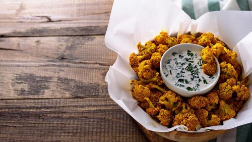 Conopidă și broccoli pané, servite cu un sos, orez simplu și salată. O idee de cină vegetariană dar cu gust