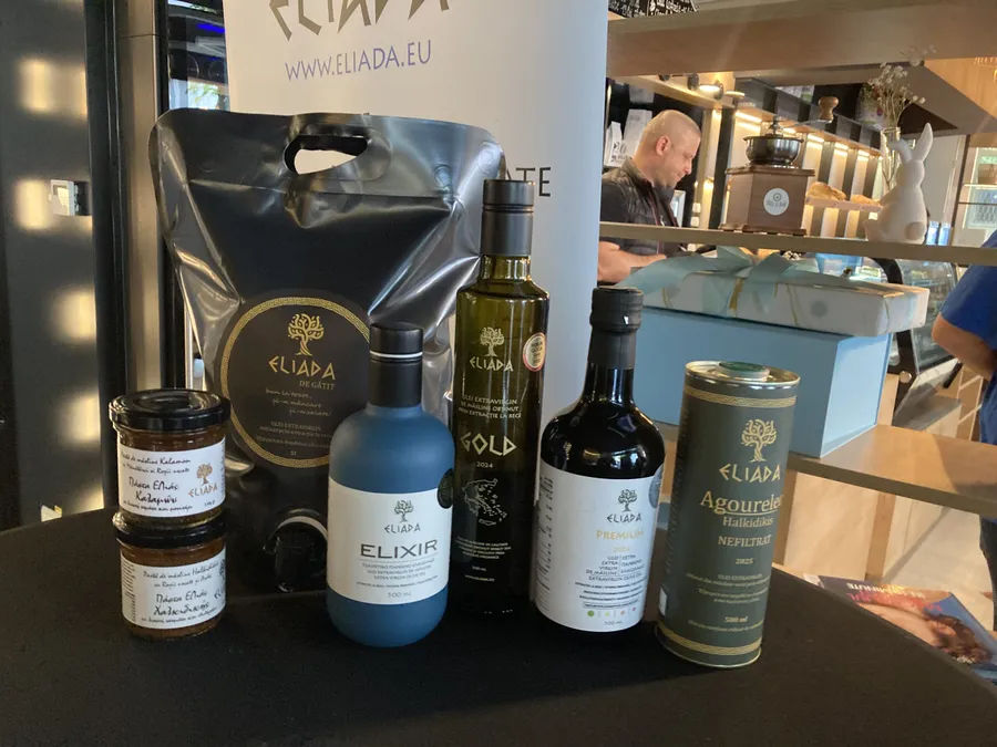 Sticlă de ulei de măsline Eliada alături de un bol cu măsline verzi și ulei proaspăt, într-un decor culinar mediteraneean.