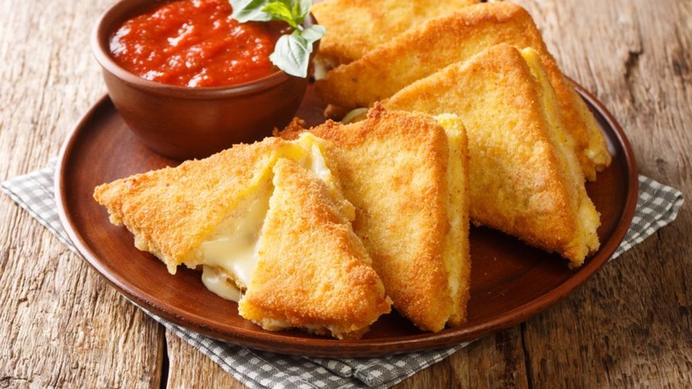 Mozzarella in carrozza, un fel de cașcaval pané 2.0. E nevoie de felii de pâine cu mozzarella între ele, date prin ou și pesmet și prăjite