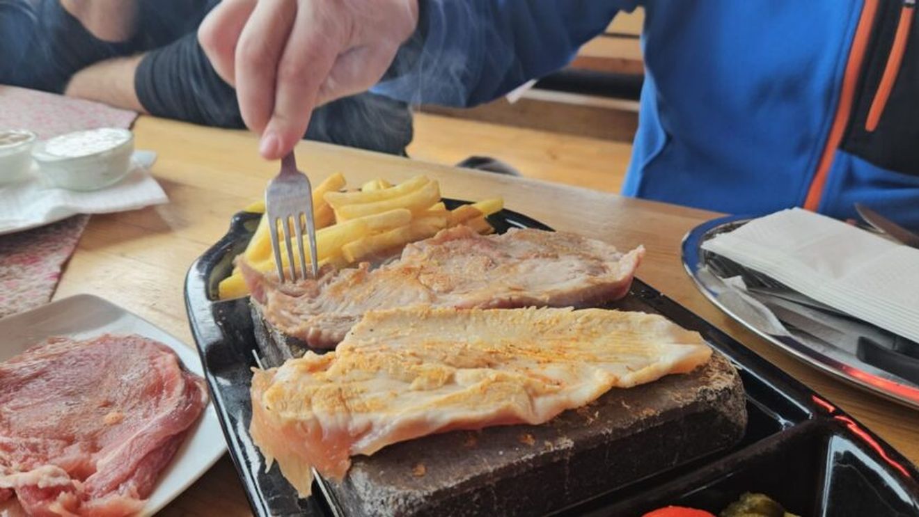 VIDEO | Experiență culinară inedită la baza pârtiei: Locul unde poți mânca friptură pe piatră încinsă, pregătită chiar de tine! Nu te aștepta la fine dining, ci la o masă autentică, gustoasă și mai ales ... accesibilă!